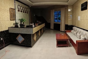 A reception area with a counter, a sofa, a coffee table, and a staircase leading to another floor.