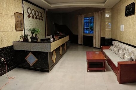 A reception area with a counter, a sofa, a coffee table, and a staircase leading to another floor.. Shujie Hotel