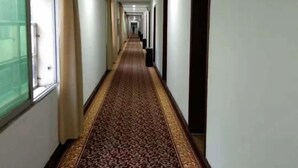 A long, narrow hallway with a patterned carpet and white walls. - Shujie Hotel (Ji'an)