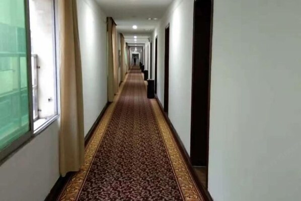 A long, narrow hallway with a patterned carpet and white walls. - Shujie Hotel (Ji'an)