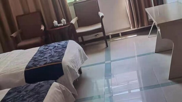 Habitación de hotel con dos camas, un escritorio, una silla y una mesita.