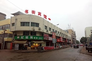 A multi-story building with a green awning, a sign with Chinese characters, and a red flag with Chinese characters.