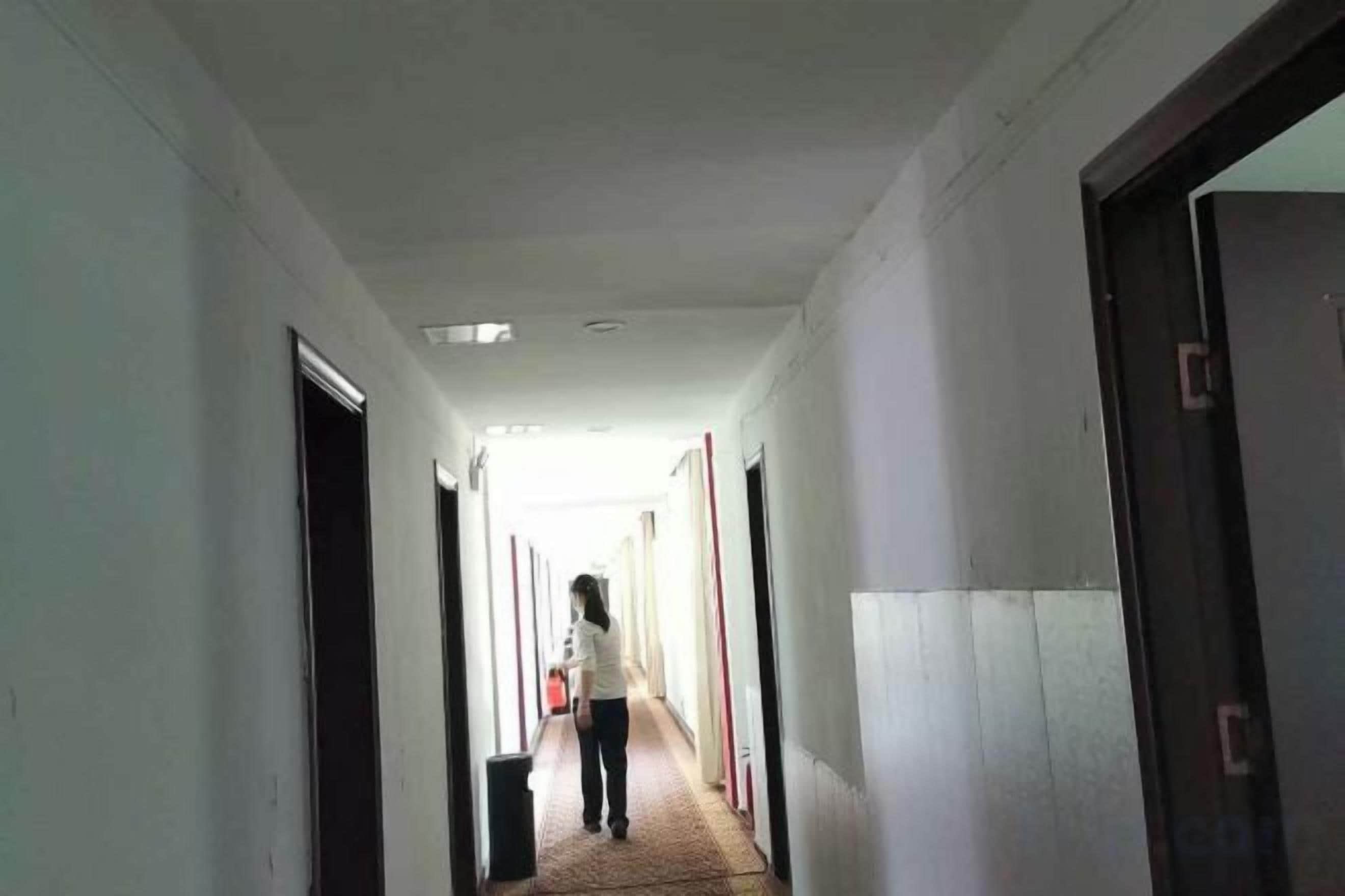A corridor with doors on both sides, leading to rooms.