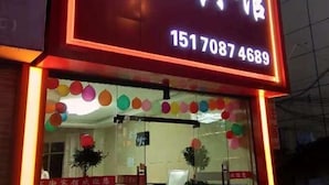 A hotel entrance with a neon sign displaying the name and contact number. - Shujie Hotel (Ji'an)