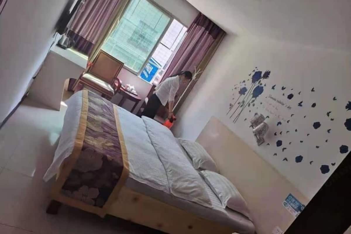 A bedroom with a bed, a desk, and a window with curtains.
