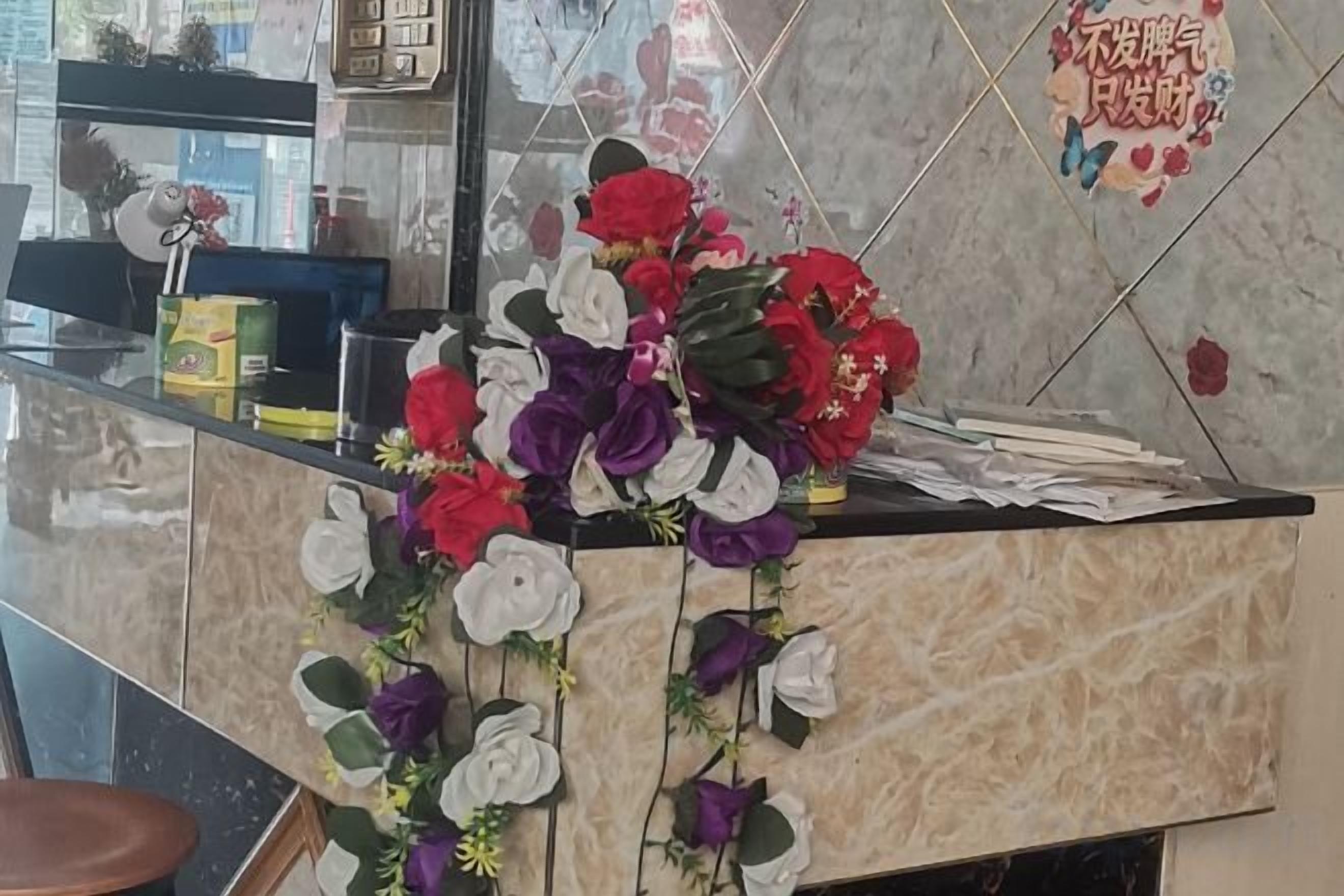 A reception desk with a floral arrangement and a welcome sign.