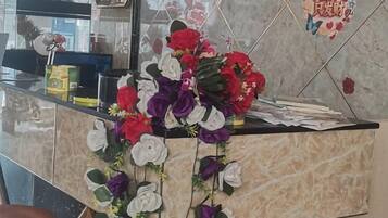 A reception desk with a floral arrangement and a welcome sign.