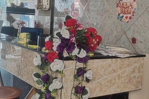 Een receptiebalie met een bloemstuk en een welkomstbord.