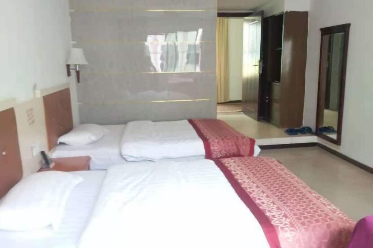 A hotel room with two beds, a mirror, and a door leading to a bathroom.