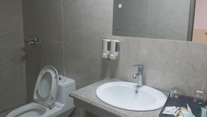 A bathroom with a toilet, sink, and mirror. - Shujie Hotel (Ji'an)