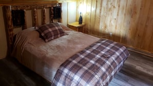 Une chambre dans une cabane en bois, avec un lit, une petite table et une table de chevet.