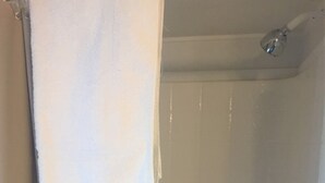 Een badkamer met een witte douchegordijn, een witte handdoek links hangend, en een witte douchekraan.