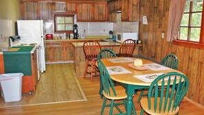 Une cuisine rustique avec des meubles de rangement en bois, une table à manger avec des chaises et un réfrigérateur.