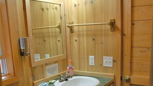 Une salle de bain en bois avec des toilettes, un lavabo et un miroir.