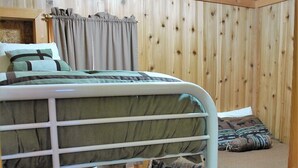 Une chambre avec un lit superposé, un intérieur en bois, une petite armoire en bois et un rideau.