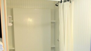 Un baño con inodoro, cabina de ducha y dispensador de papel higiénico.