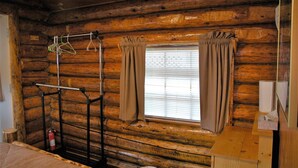 Une chambre de style rustique avec une fenêtre, des rideaux, un porte-manteau et un extincteur.