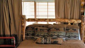 Un lit en bois rustique, agrémenté d’oreillers et de rideaux aux motifs animaliers.