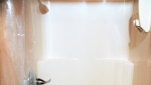 Une cabine de douche blanche et vide, avec un drain au fond.