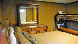 Habitación de hotel con cómoda de madera, un espejo grande, una cama litera y una cama con almohadas estampadas.