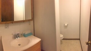 Un baño con lavamanos, espejo e inodoro.