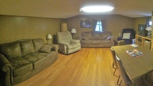 Una sala de estar con un sofá, un sillón y una mesa de comedor con sillas.