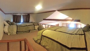 Quarto com duas camas, uma cadeira de madeira e teto inclinado.