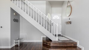 Un escalier avec des rampes blanches et des marches en bois menant à une porte.