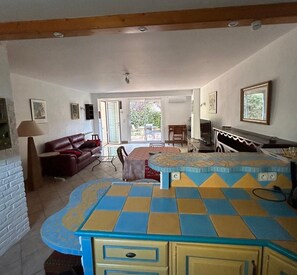 A living room with a sofa, a coffee table, and a TV. There is a sliding glass door leading to a balcony.
