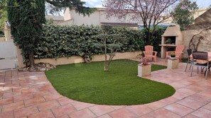 A landscaped patio with a curved grass area, outdoor seating, and a stone wall. - Quiet ground-floor apartment near the city center. (Salon-de-Provence)