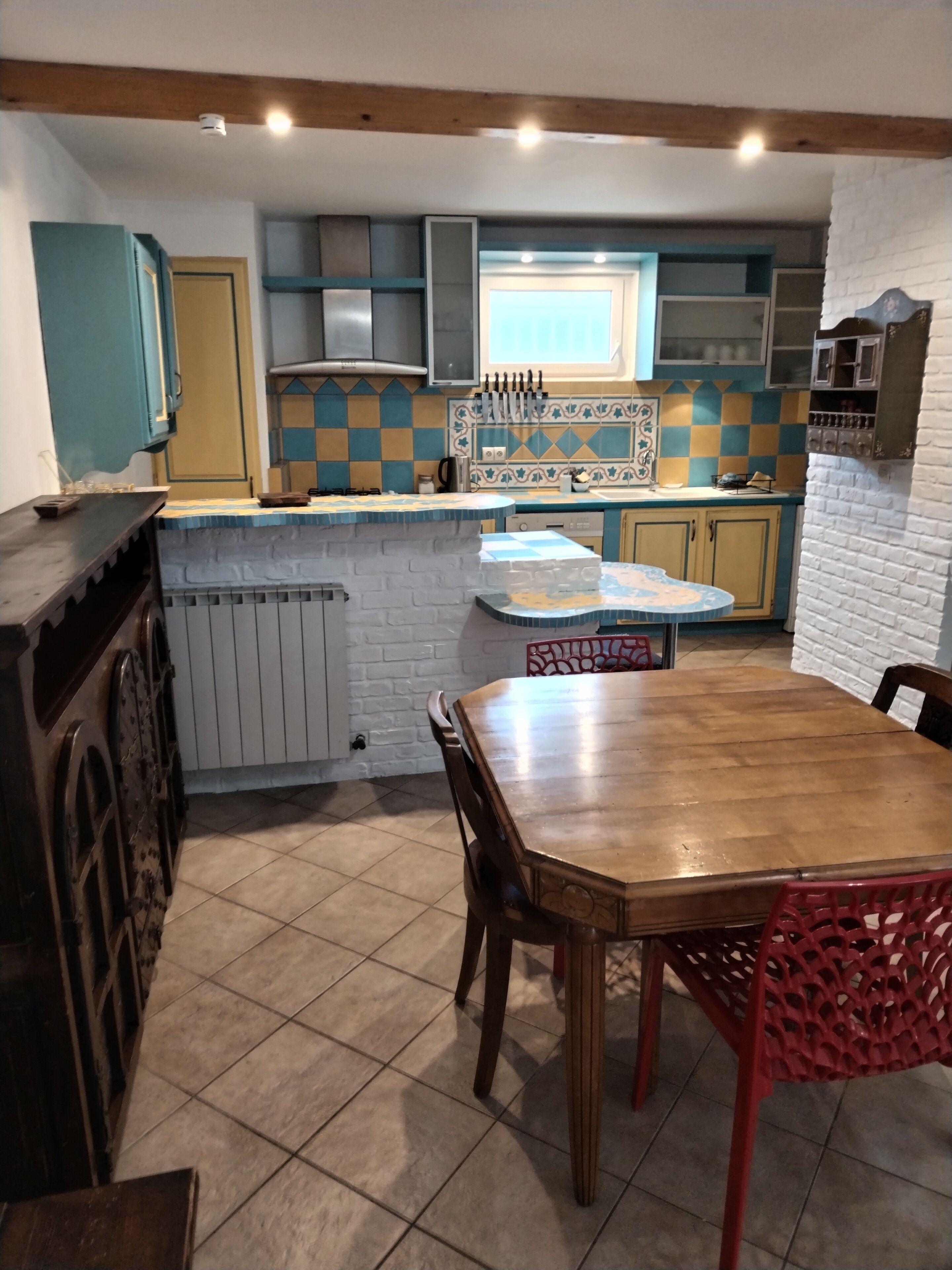 Een keuken met een houten tafel en stoelen, een raam en een witte bakstenen muur.