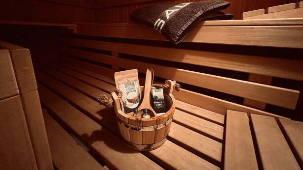 Un banco de madera con una cesta tejida que contiene botellas y una toalla.