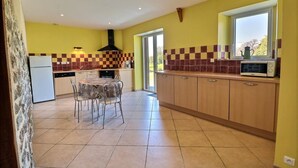 Una cocina compacta con una mesa de comedor, sillas, un refrigerador y un microondas.