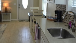 Una cocina con lavabo, encimera y puerta que da a otra habitación.