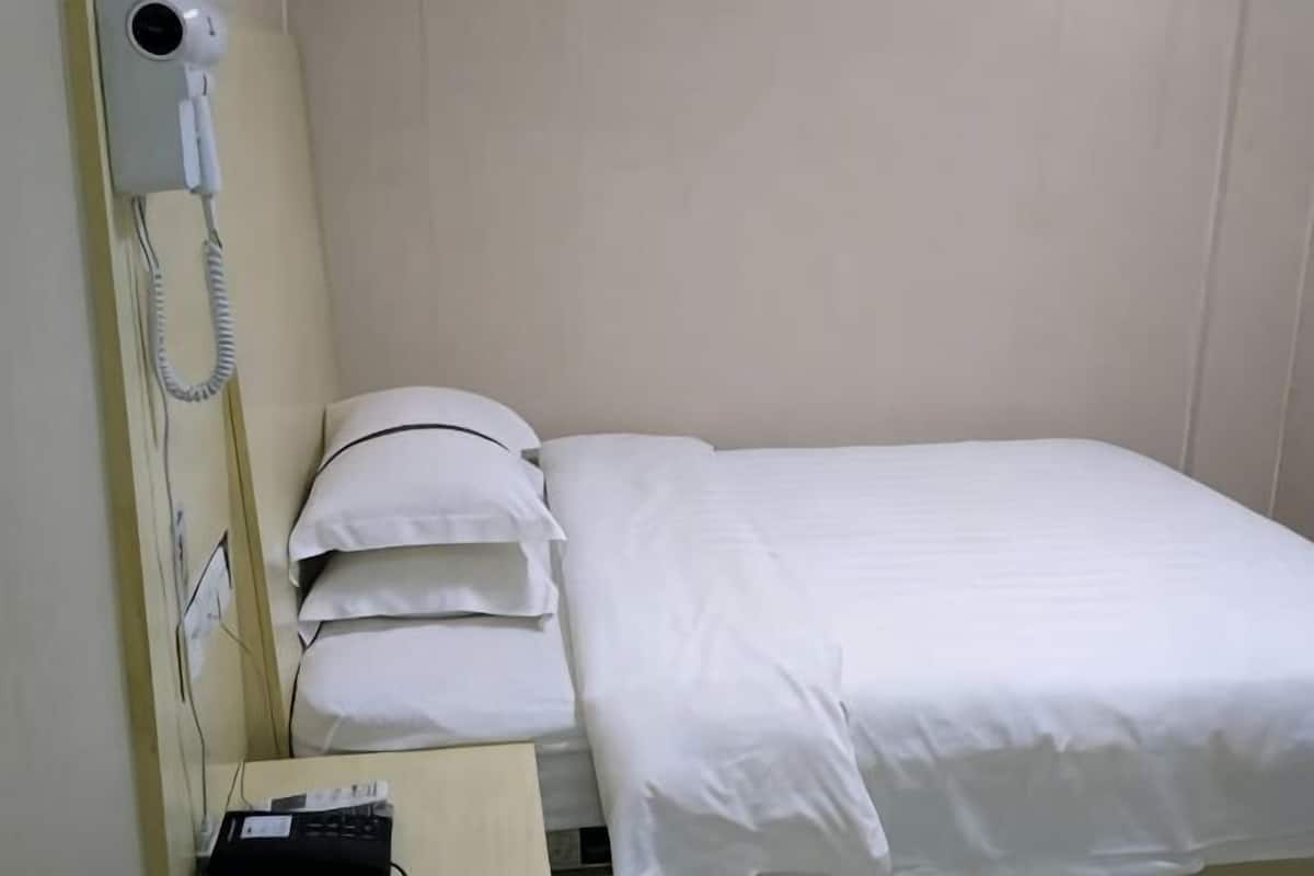 A hotel room with a bed, a hairdryer, and a phone on the nightstand.