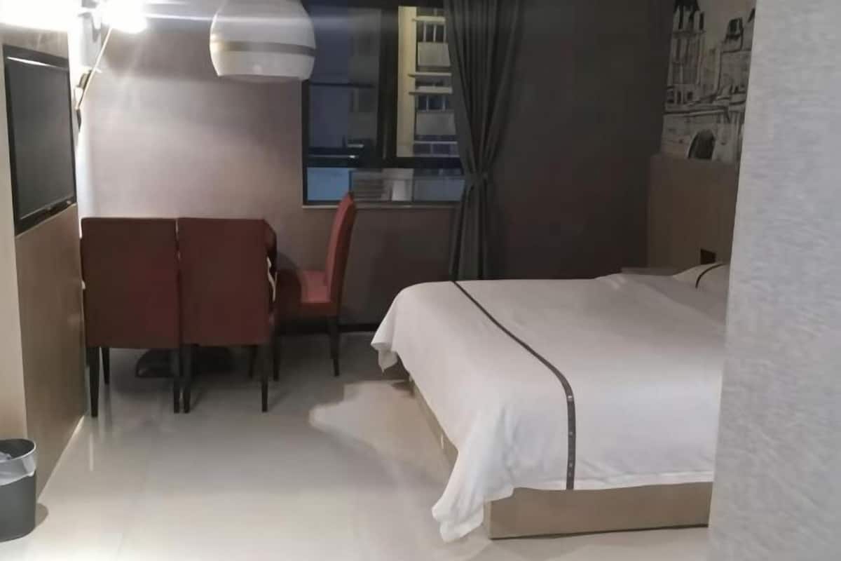 A hotel room with a bed, a desk, and a chair.