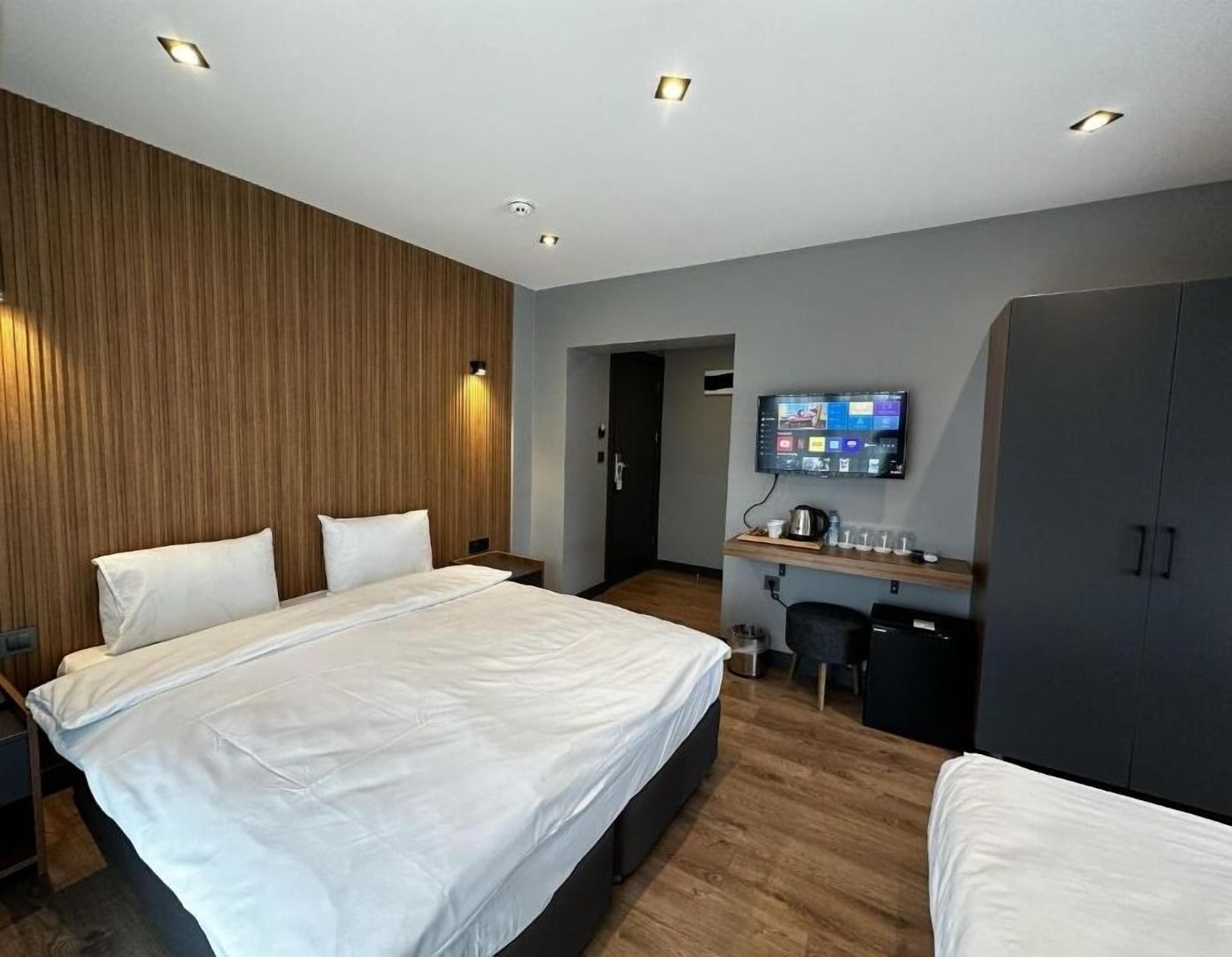 Een moderne hotelkamer met een groot bed, een bureau met een flatscreen televisie en een kledingkast.