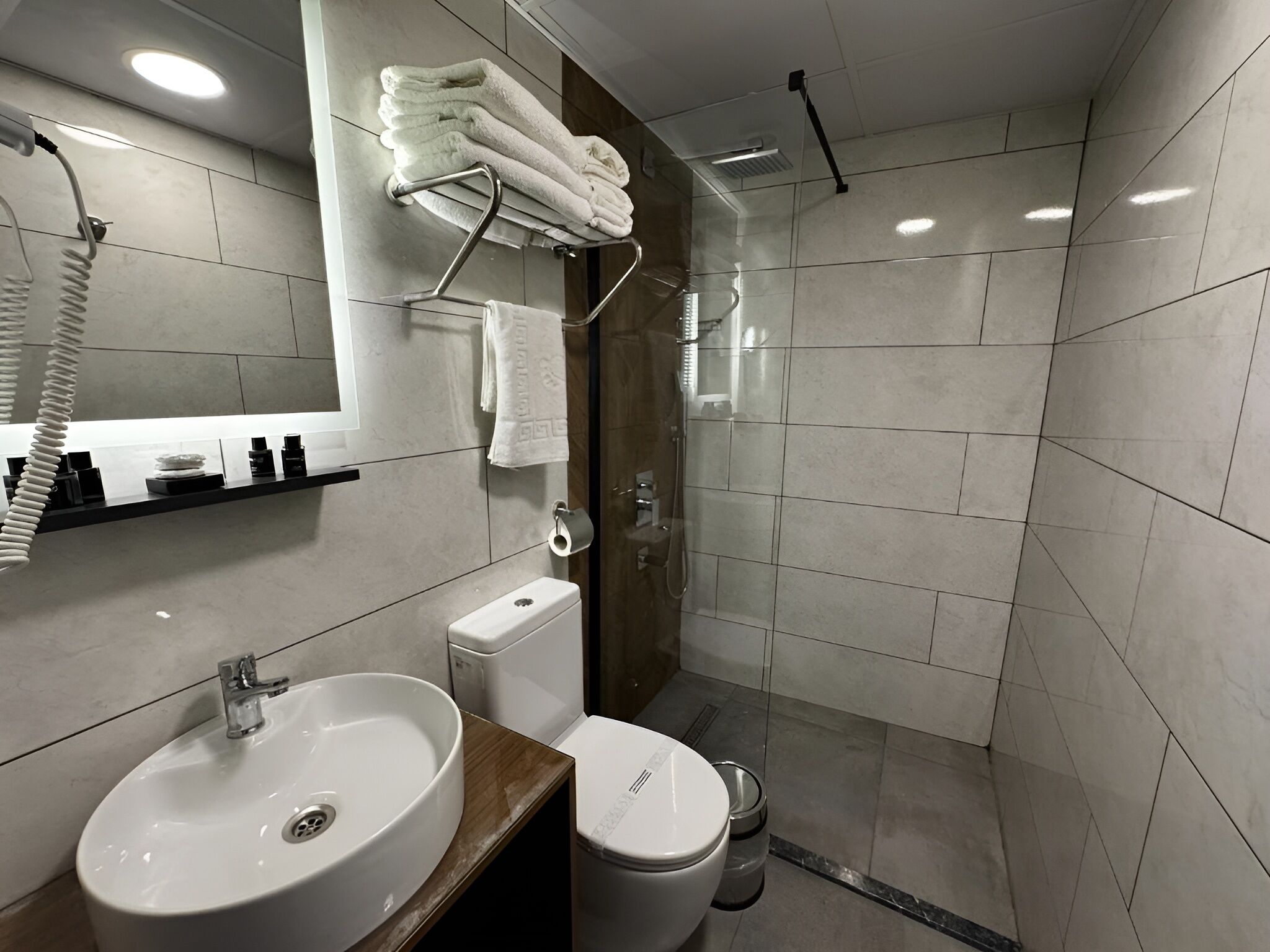 Un baño moderno con lavamanos, inodoro y zona de ducha.