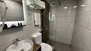 Un baño moderno con lavamanos, inodoro y zona de ducha.