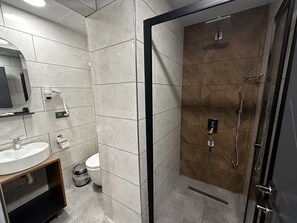 Un baño moderno con ducha de vidrio, lavamanos y un inodoro.