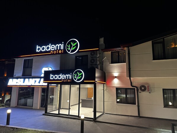 Un hotel llamado 'bademi hotel' con una fachada moderna y señalización iluminada.