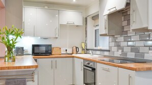 A modern kitchen with white cabinets, a microwave, a kettle, and a wooden countertop. - 3 bedroom accommodation in Southerness, near Sandyhills (Southerness, near Sandyhills)