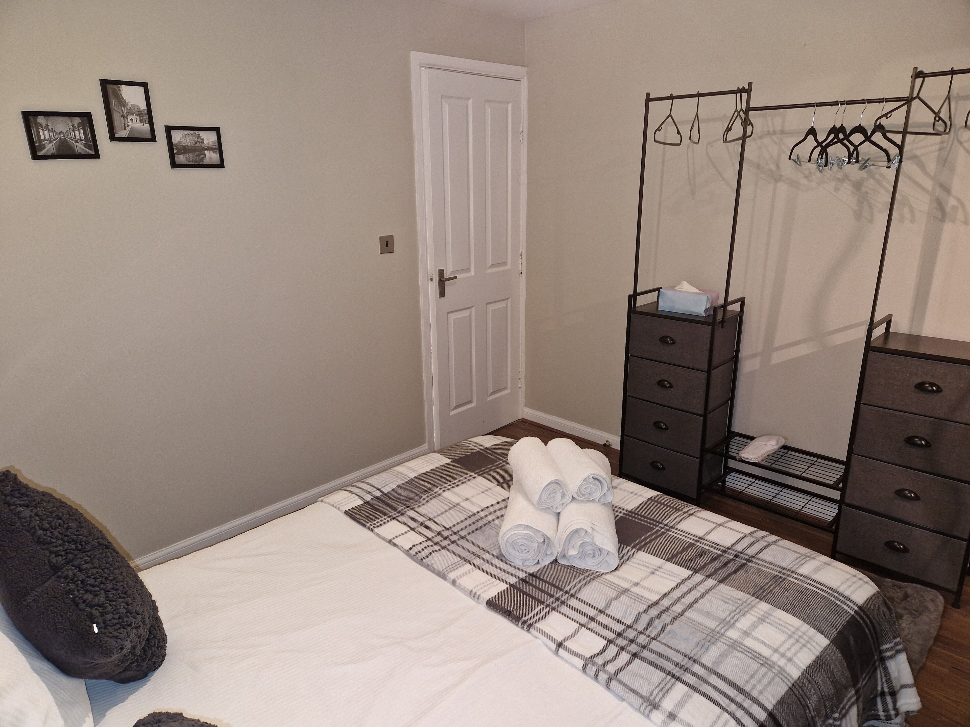 Una camera da letto con un letto, una cassettiera, un armadio e tre quadri appesi al muro.