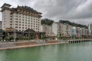 Un hôtel situé au bord de l’eau, avec plusieurs étages, un quai et une architecture de style traditionnel.