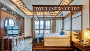 A four-poster bed with a television on a wooden cabinet, a bedside table with a lamp, and a view of the city through large windows. - Taijiang Hotel (Taijiang)