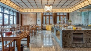 A spacious dining area with wooden tables and chairs, a marble floor, and a central island with a sink and counter. - Taijiang Hotel (Taijiang)