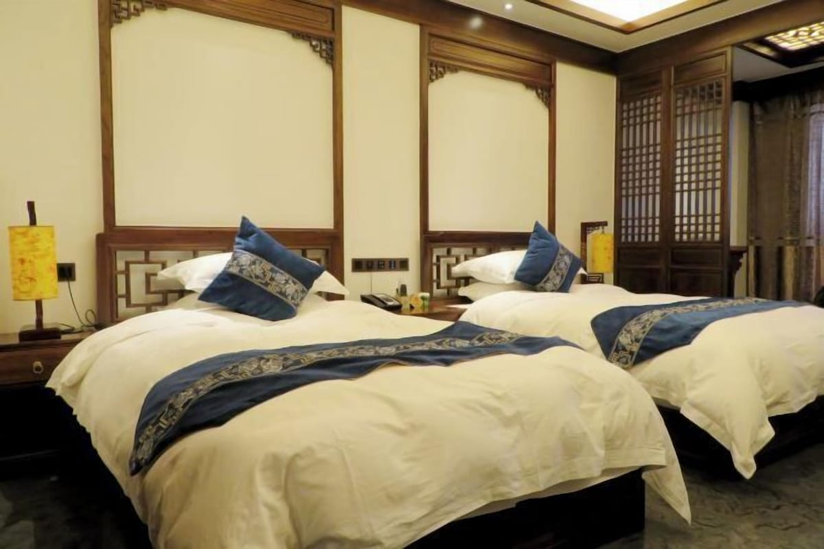 Une chambre d’hôtel avec deux lits, chacun doté d’une tête de lit en bois et d’une couvre-lit bleue et blanche.