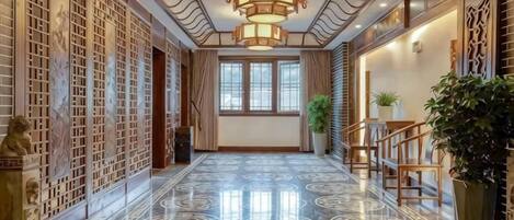 A hallway with a marble floor, traditional decor, and a staircase.