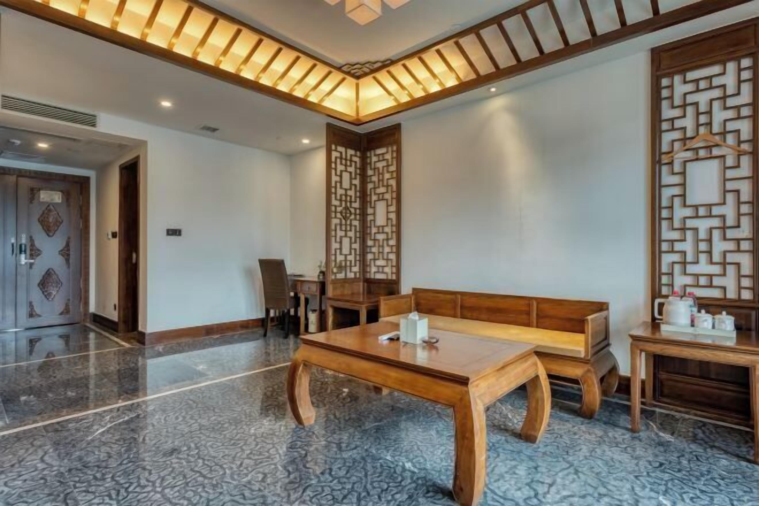 A room with a wooden table, a bench, and a decorative screen.
