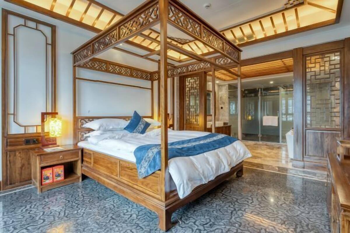 Une chambre à coucher de style traditionnel, avec un lit à baldaquin, une table de chevet en bois et un parquet à motifs.